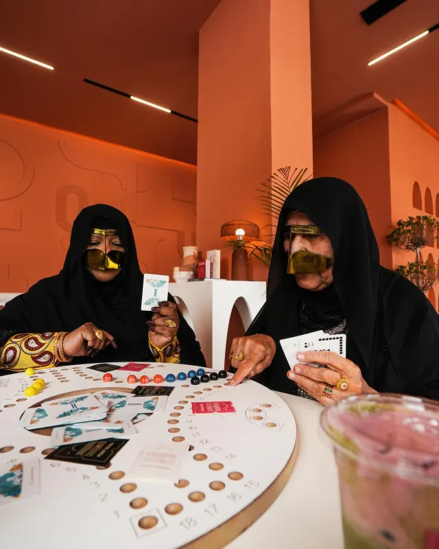 Emirati women playing cards over drinks at Point Seven Coffee, lifestyle photography