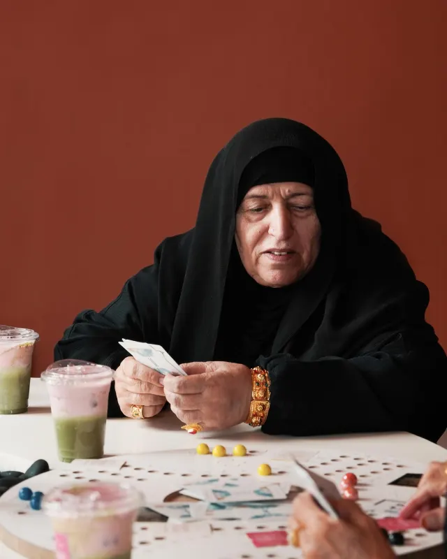 Emirati woman playing cards at a table at Point Seven Coffee