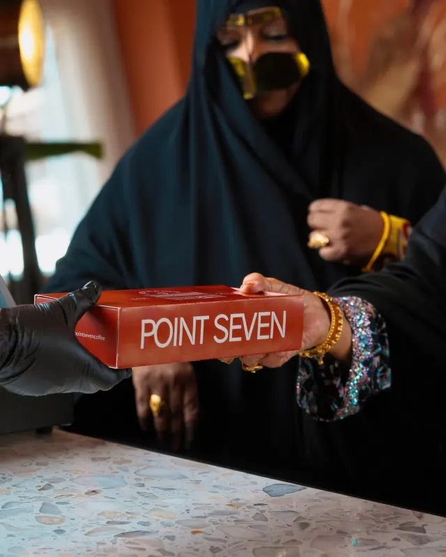 Point Seven Coffee box handed across the table, product lifestyle photography